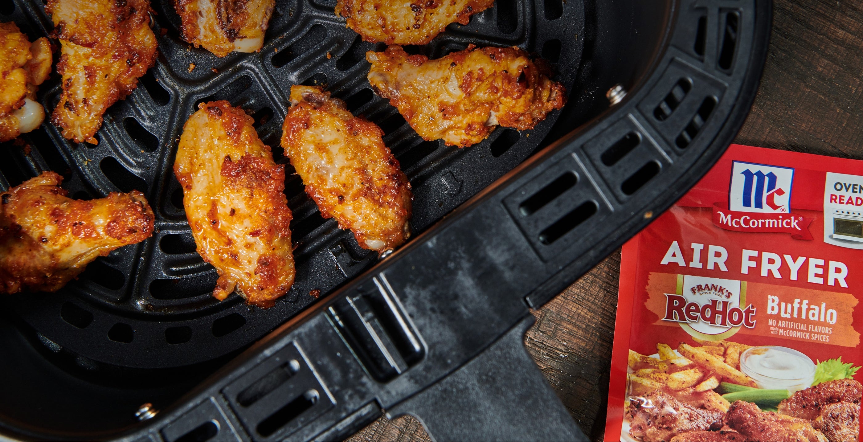 chicken wings in an air fryer with a packet of frank's redhot buffalo air fryer seasoning