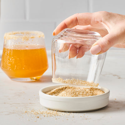 Glass rimmed with salted caramel sugar, McCormick Salted Caramel Finishing Sugar bottle, and drink