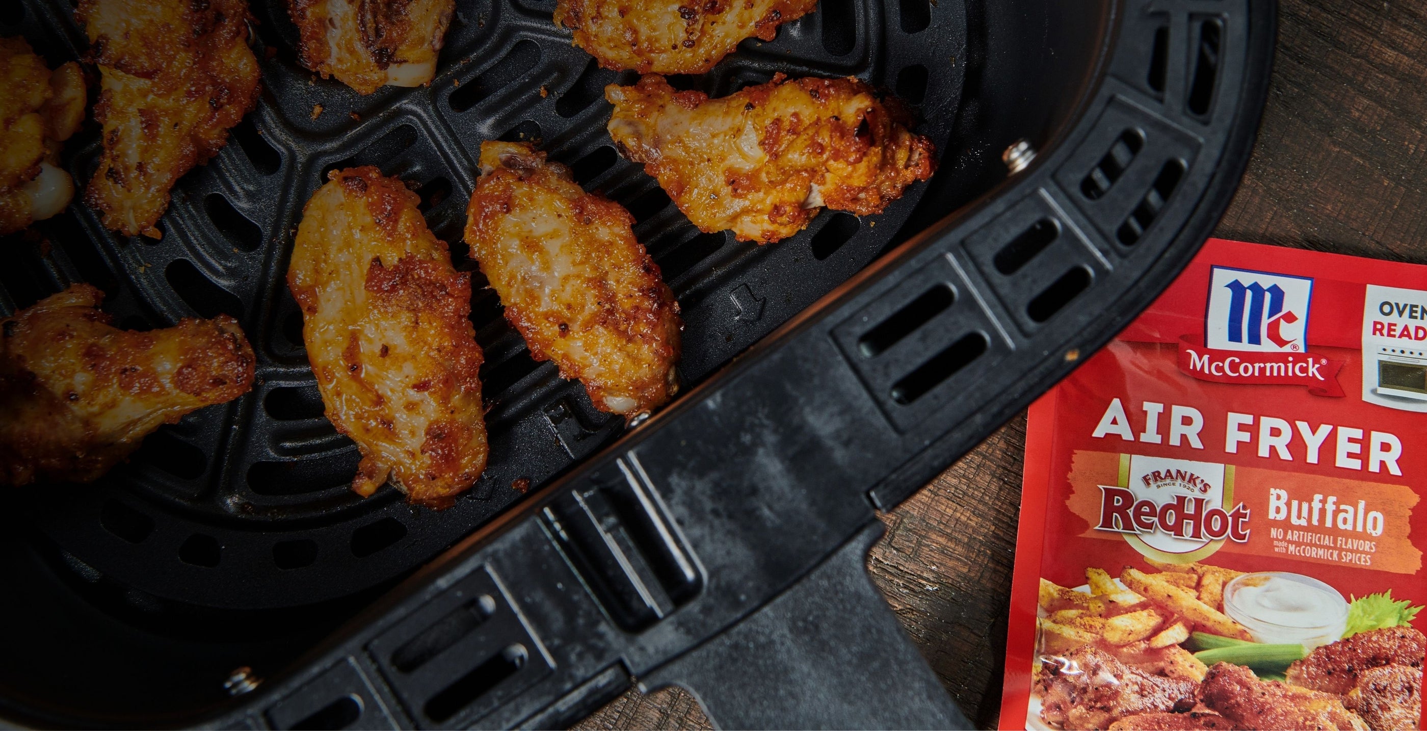 chicken wings in an air fryer with a packet of frank's redhot buffalo air fryer seasoning