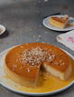 flan cake with a slice cut out topped with toasted coconut