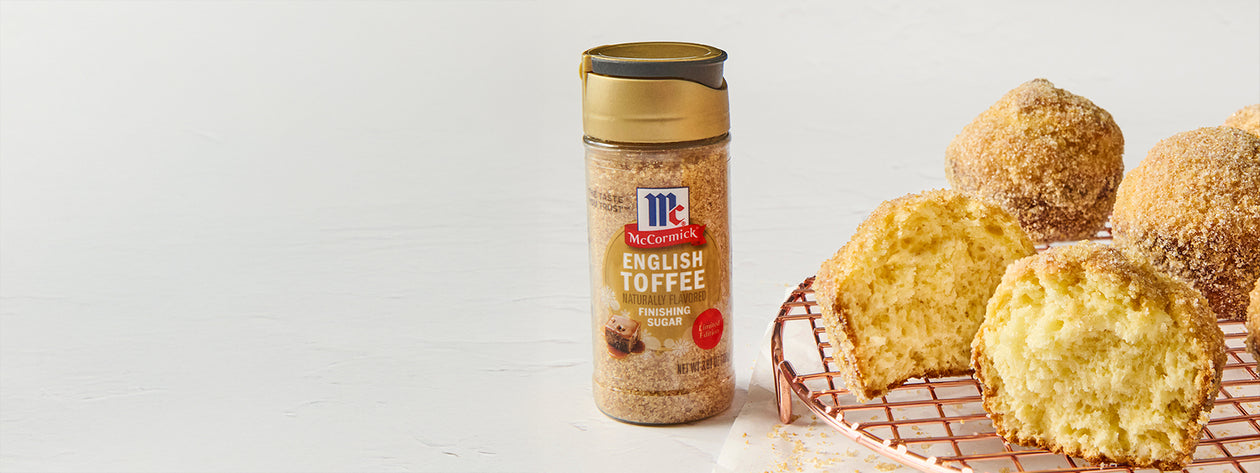 McCormick English Toffee Finishing Sugar next to golden muffins coated with toffee sugar on a copper cooling rack