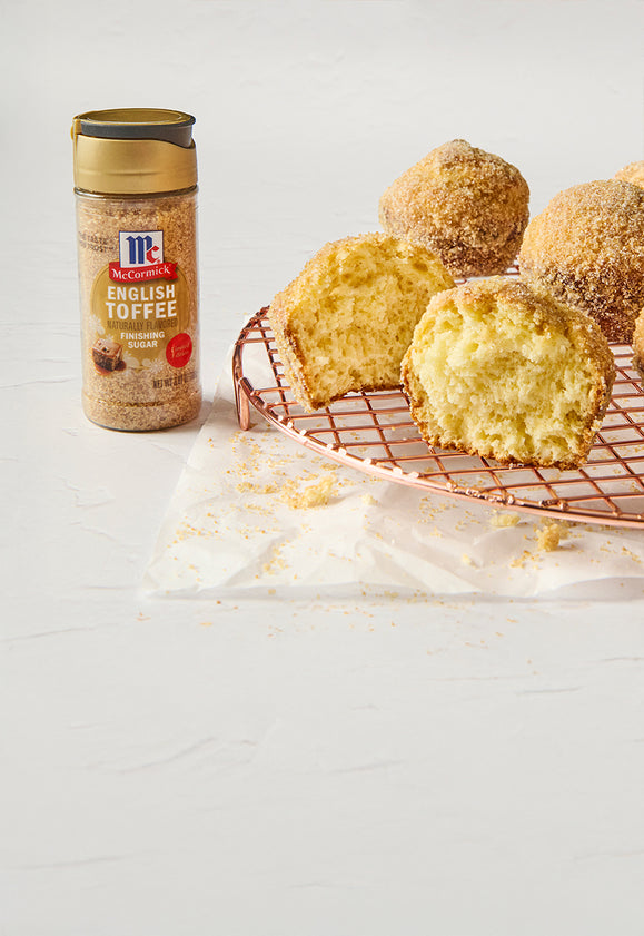 McCormick English Toffee Finishing Sugar next to golden muffins coated with toffee sugar on a copper cooling rack