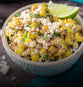 corn and cotija cheese in a bowl with a slice of lime