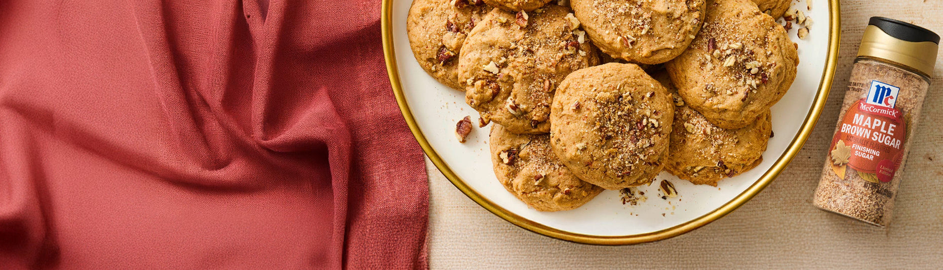 Plate of cookies with a bottle of maple syrup on a red fabric background