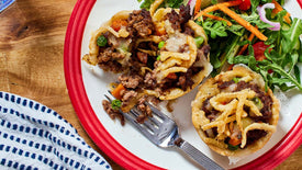 mini beef pot pies on a plate with red trim with a side salad