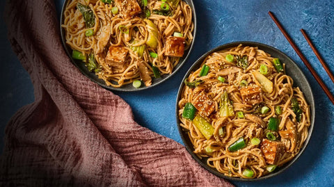 two noodle bowls with tofu scallions and sesame seeds with chop sticks