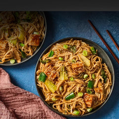 two noodle bowls with tofu scallions and sesame seeds with chop sticks