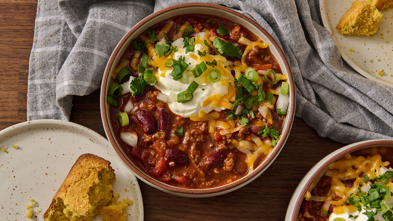 Bowl of Simple Chili topped with Sour Cream, Green Onions and Shredded Cheese