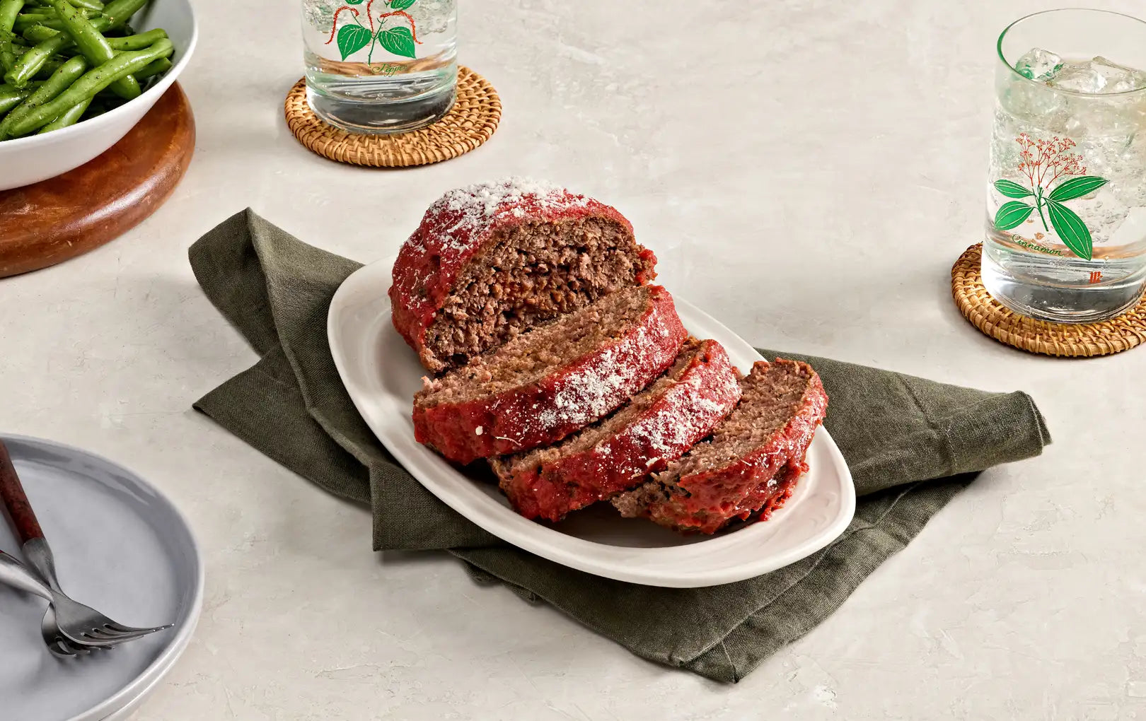 italian meatloaf with a serving of green beans in the background