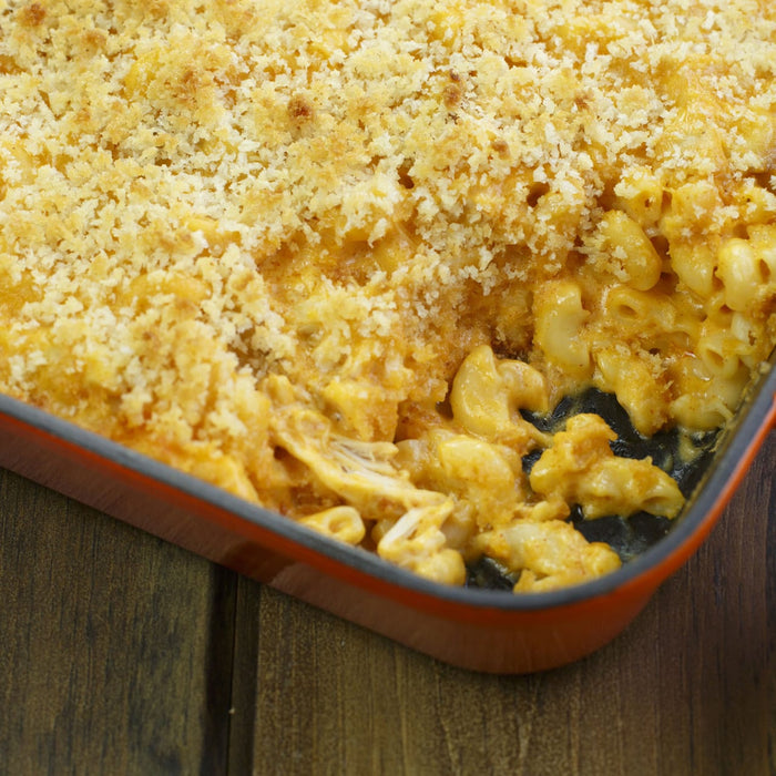 ['A close-up of a casserole dish filled with macaroni and cheese topped with breadcrumbs.']