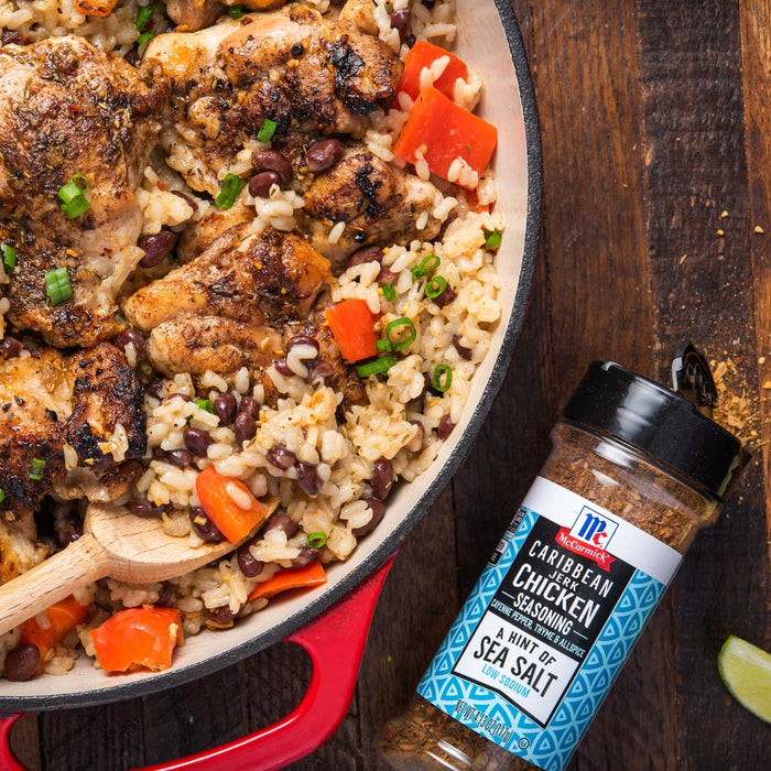 A close-up of a skillet with Caribbean Jerk Chicken and rice, next to a bottle of McCormick Caribbean Jerk Chicken Seasoning.