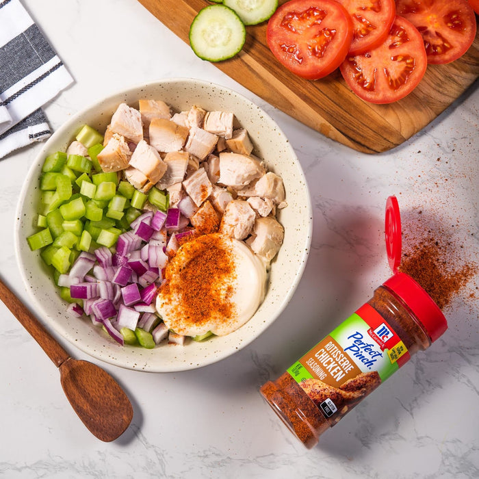 A bowl of chopped chicken, celery, and red onion with mayonnaise and McCormick Perfect Pinch Rotisserie Chicken seasoning.