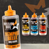A large bottle of Mission Bbq Memphis Belle 15.5 Oz BBQ sauce stands in the foreground, with three smaller bottles of Mission BBQ KC Classic, Smoky Mountain, and Texas Twang BBQ sauces visible behind it.
