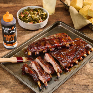 A tray of ribs glazed with Mission BBQ Memphis Belle BBQ Sauce is served with collard greens and cornbread.