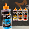 A large bottle of Mission Bbq Blue Ridge Smoky Mountain 15 Oz BBQ sauce stands in the foreground, accompanied by three smaller bottles of Mission BBQ sauces in KC Classic, Memphis Belle, and Texas Twang flavors.