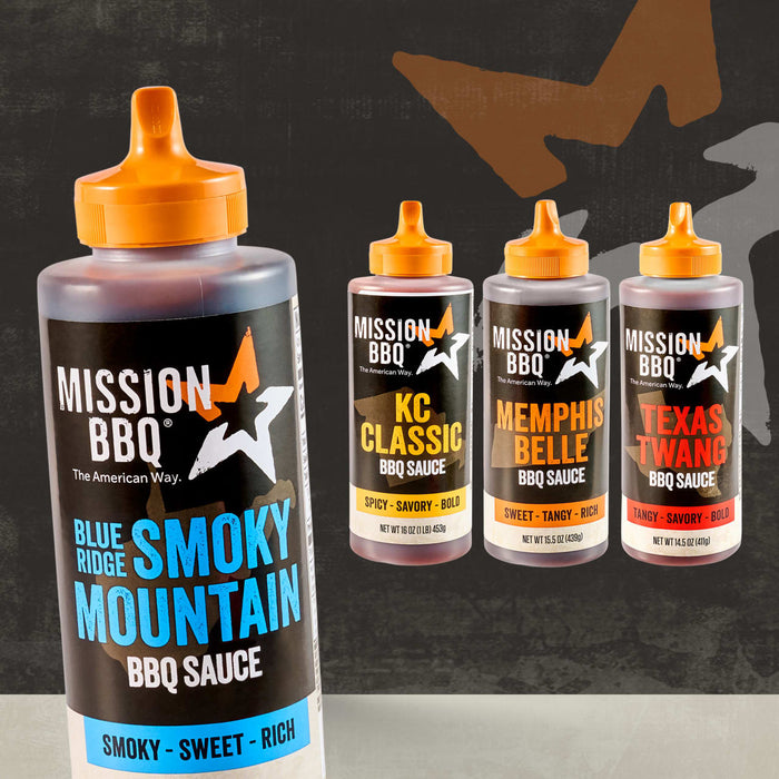 A large bottle of Mission Bbq Blue Ridge Smoky Mountain 15 Oz BBQ sauce stands in the foreground, accompanied by three smaller bottles of Mission BBQ sauces in KC Classic, Memphis Belle, and Texas Twang flavors.