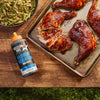 A bottle of Mission BBQ Blue Ridge Smoky Mountain BBQ Sauce sits next to a tray of glazed chicken and a bowl of green beans.