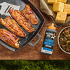 A bottle of Mission BBQ Blue Ridge Smoky Mountain BBQ Sauce is displayed with barbecued fish, cornbread, and collard greens.