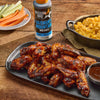Mission BBQ Blue Ridge Smoky Mountain BBQ Sauce is served with chicken wings, mac and cheese, and carrot and celery sticks.