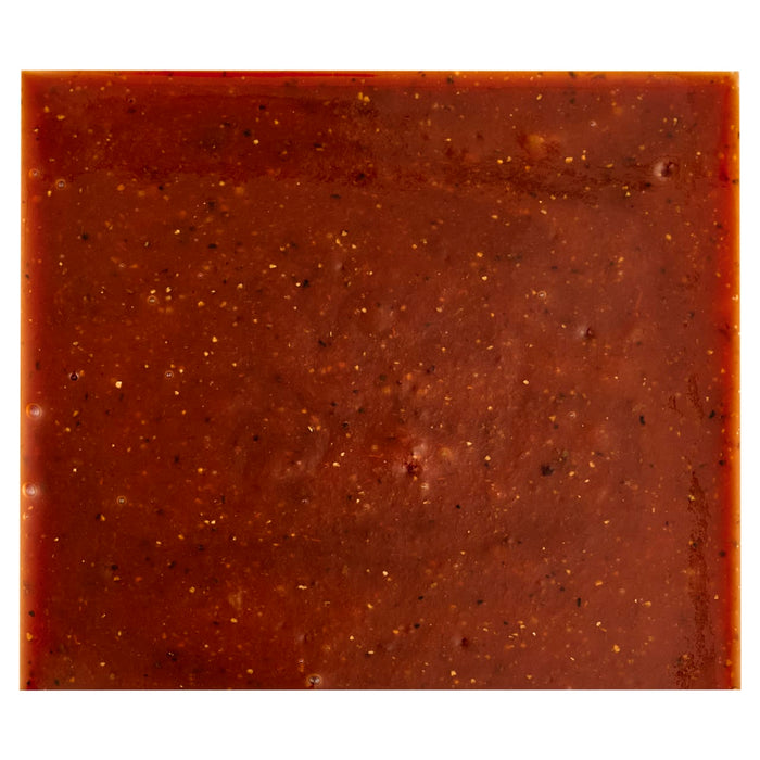 A close-up of a square of dark red fruit leather with visible flecks of spices.