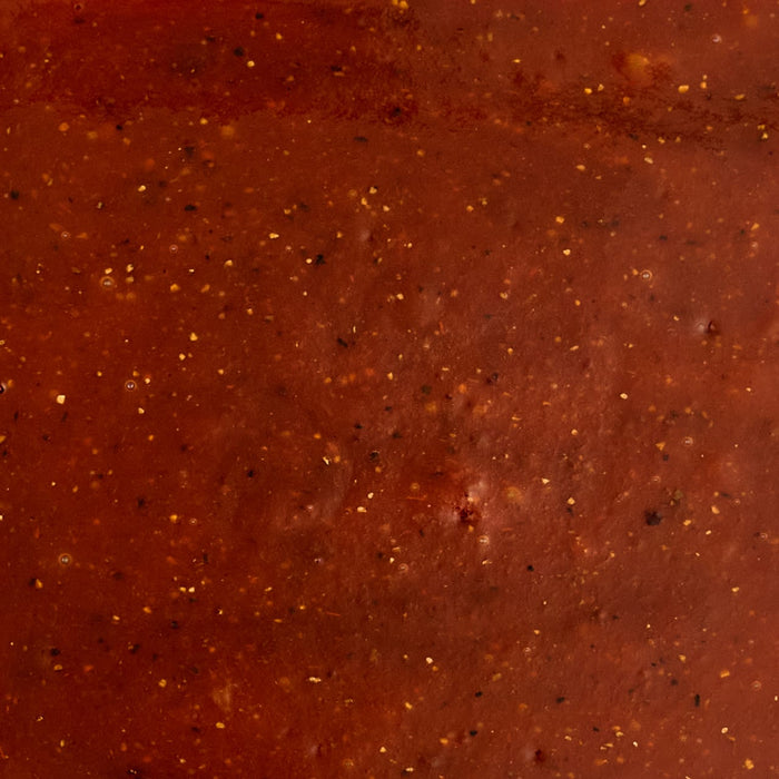 A close-up texture shot of Mission Bbq Texas Twang Bold Barbecue Sauce Plastic Squeeze Bottle 14.5 Oz, showing the rich red color and specks of spices.