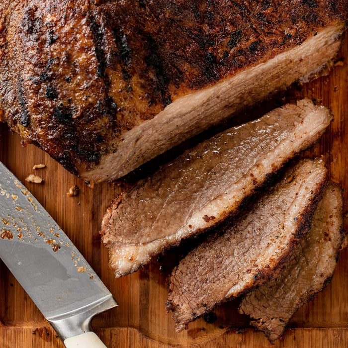 A close-up of a sliced brisket on a wooden cutting board.