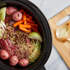 A slow cooker filled with ingredients for corned beef and cabbage.