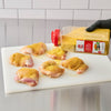 Raw chicken thighs are being seasoned with a McCormick spice blend on a white cutting board.