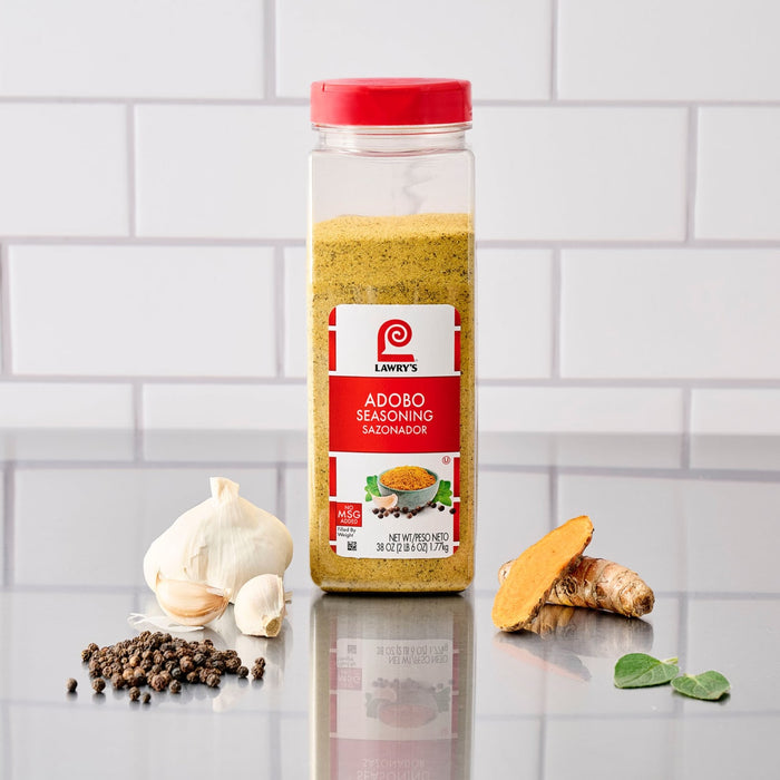 A bottle of Just Raita Seasoning Mix is displayed with garlic, peppercorns, turmeric, and a green leaf, highlighting its natural ingredients.