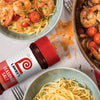 A bottle of Lawry's Seasoned Salt next to a bowl of pasta with shrimp and tomatoes.