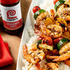 A plate of grilled shrimp skewers with vegetables and rice, next to a bottle of Lawry's Seasoned Salt.