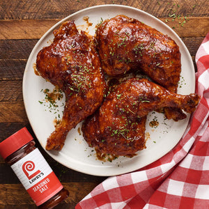 Three Lawry's seasoned chicken legs on a white plate with a red and white checkered napkin.