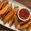 A plate of crispy sweet potato fries with a side of ketchup.