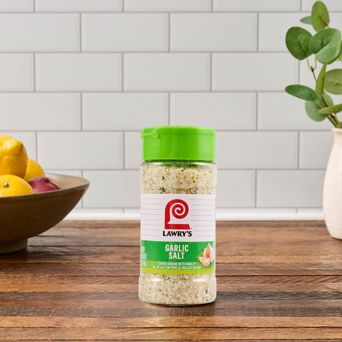A container of Lawry's Garlic Salt sits on a wooden countertop.