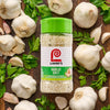 A bottle of Lawry's Garlic Salt is surrounded by fresh garlic bulbs and parsley.