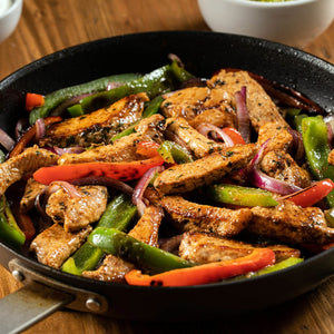 A skillet filled with sizzling fajitas, featuring strips of seasoned meat, colorful bell peppers, and red onions.