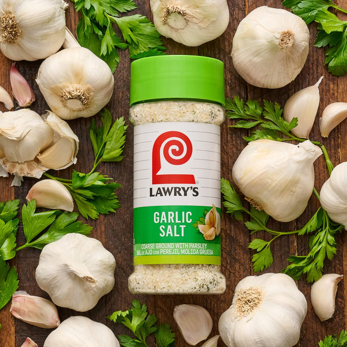 A jar of Lawry's Garlic Salt surrounded by garlic cloves and parsley.