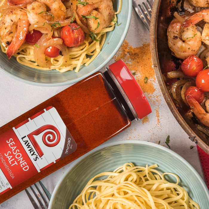 A bottle of Lawry's Seasoned Salt is featured next to two bowls of shrimp pasta.