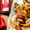 A plate of grilled shrimp and vegetable skewers served over rice, seasoned with Lawry's Seasoned Salt.