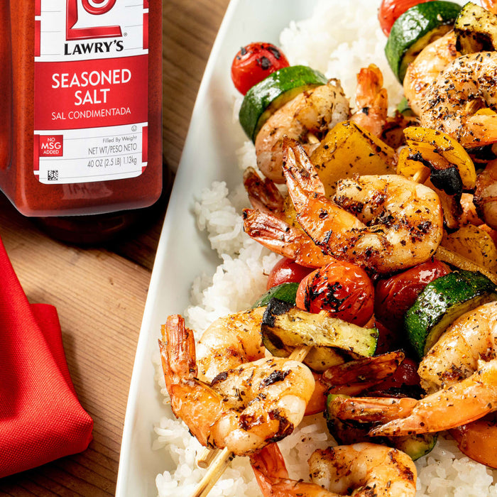 A plate of grilled shrimp and vegetable skewers served over rice, seasoned with Lawry's Seasoned Salt.
