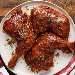 A plate of BBQ chicken pieces, likely featuring a brand like the one partially visible in the corner.