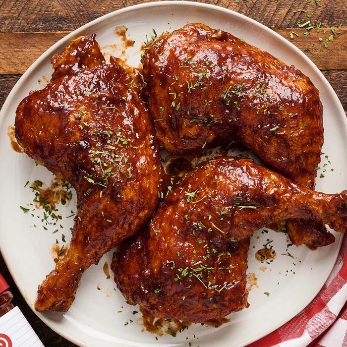 A plate of BBQ chicken pieces, likely featuring a brand like the one partially visible in the corner.