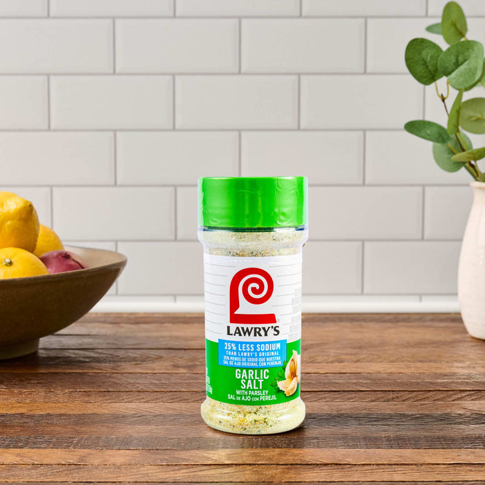 A container of Lawry's Seasoned Salt sits on a wooden countertop.