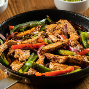 A skillet filled with sizzling chicken fajitas, featuring colorful bell peppers and red onions.