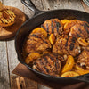 A cast iron skillet filled with grilled chicken and peaches.