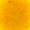 A close-up shot of a vibrant yellow liquid with small particles suspended within it.