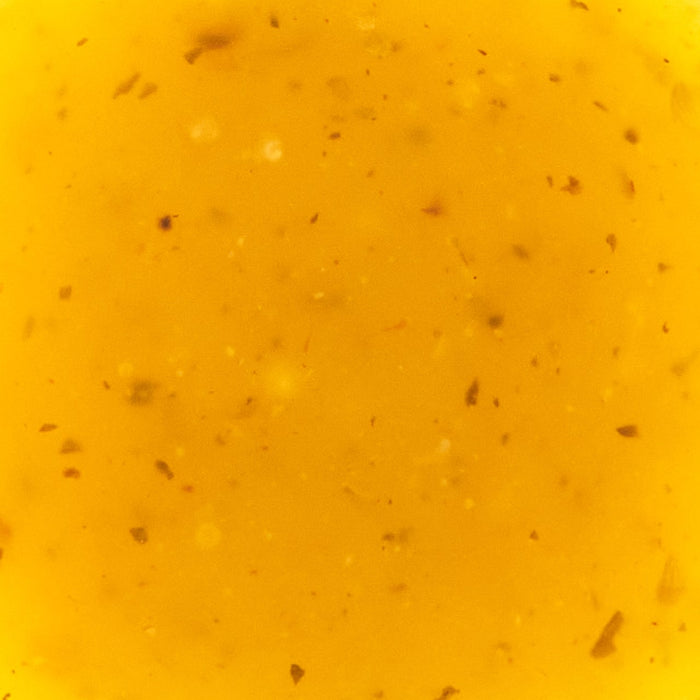 A close-up shot of a vibrant yellow liquid with small particles suspended within it.