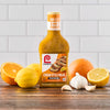 A bottle of Lawrys Cuban Style Mojo Marinade with oranges lemons and garlic.