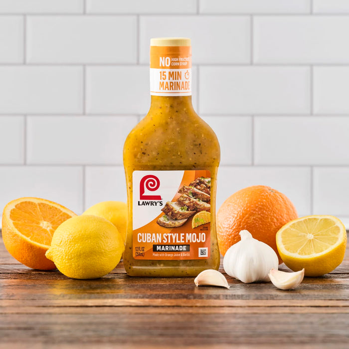 A bottle of Lawrys Cuban Style Mojo Marinade with oranges lemons and garlic.