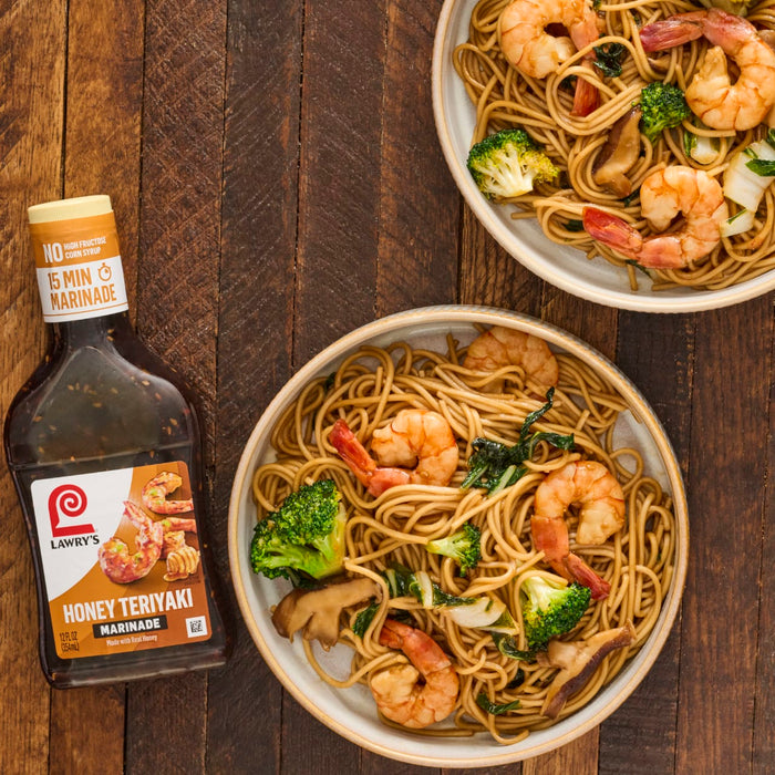 A bowl of Lawrys Honey Teriyaki Marinade shrimp stir fry with noodles broccoli and mushrooms.